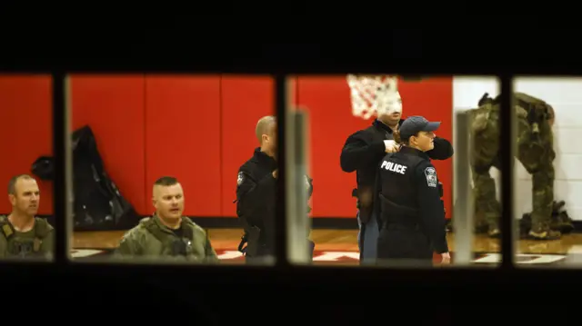 Law enforcement officers gather in school gymnasium amid manhunt