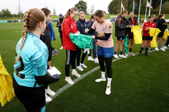 Earps signs a shirt for a young fan after a training session day.