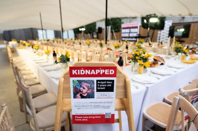 Flyer with name of 3-year-old Avigail Idan attached to a high chair at The Empty Shabbat Table installation