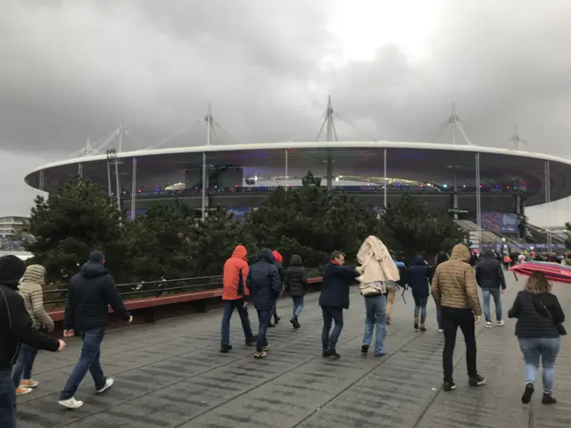 Stade de France with fans sheltering under umbrellas