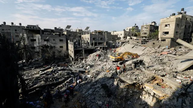 Emergency service workers pick through the rubble of houses destroyed by Israeli strikes for casualties