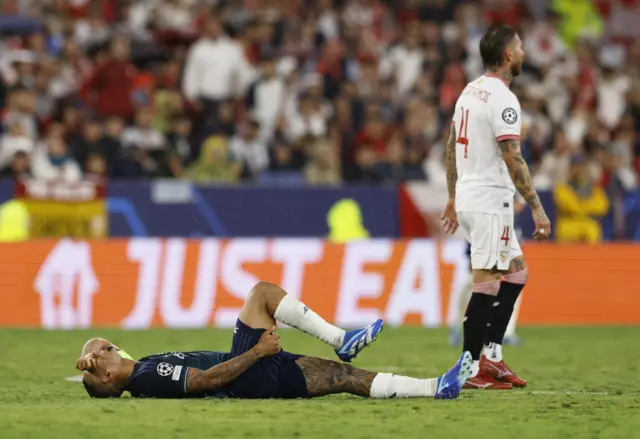 Jesus lies stricken on the pitch in Seville, covering his eyes with his hand.