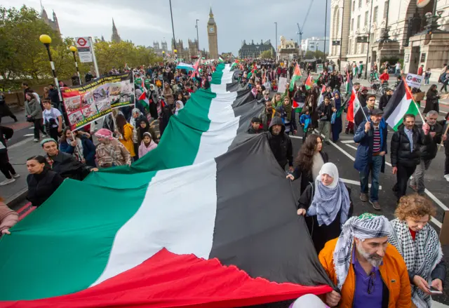 Protesters hold a massive Palestinian flag at a rally in London