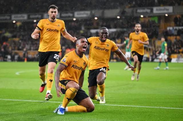 Lemina falls to his knees and shouts in celebration of his goal, while joined by teammates.