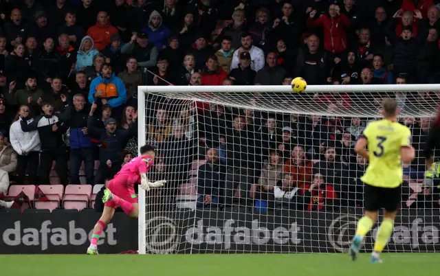 The ball flies over the head of Trafford into the net as a defender watches on.