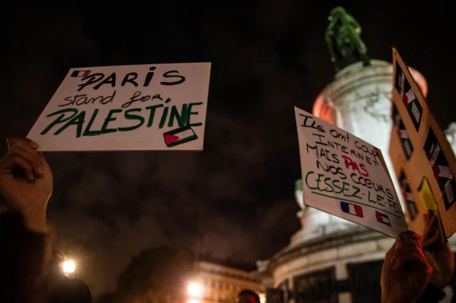 In Paris, one sign reads: "They cut the internet but not our hearts. Ceasefire"