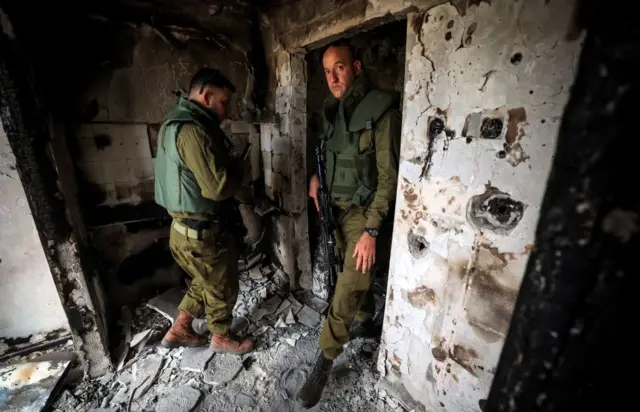 Israeli soldiers enter a home in Kibbutz Kfar Aza, one of the kibbutzim attacked by Palestinian Hamas militants earlier this month, close to the southern Israeli border with the Gaza Strip on October 27, 2023,