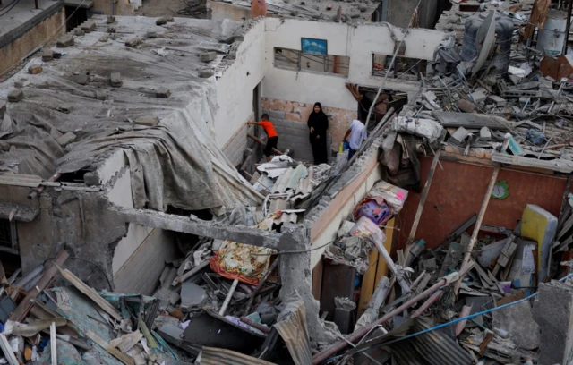 Emergency personnel and people check the damage at the site of Israeli strikes on houses, amid the ongoing conflict between Israel and Palestinian Islamist group Hamas, in Khan Younis