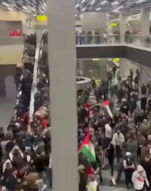 A crowd seen storming through an airport