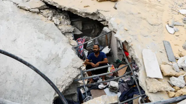 A Palestinian man sits amidst the rubble in Khan Younis following an Israeli air strike, Gaza