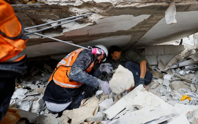 Rescue workers search in the rubble at the site of Israeli strikes on houses, amid the ongoing conflict between Israel and Palestinian Islamist group Hamas, in Khan Younis