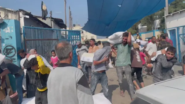 Palestinians carry food and other supplies out of the UNRWA depot at in the southern Gaza Strip