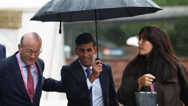 Rishi Sunak walks in the rain at Britain's Conservative Party's annual conference in Manchester