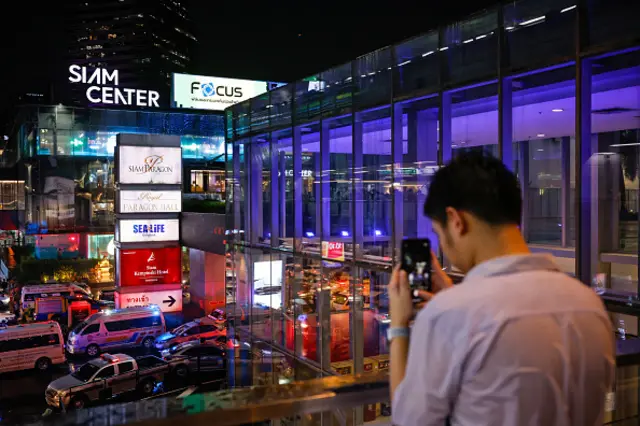 A man takes a photo of the Siam Paragon shopping centre after a teenager opened fire inside