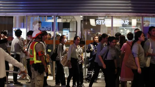 Shoppers are evacuated at an entrance of Siam Paragon mall