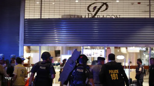 Police officers guard an entrance of Siam Paragon Mall following gunshots in Bangkok