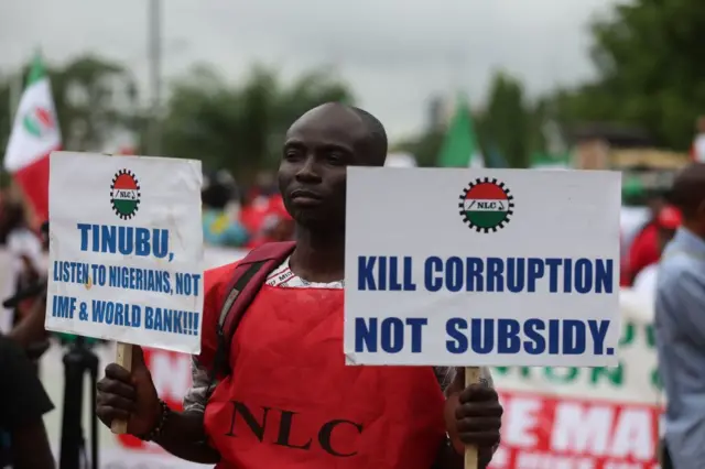 Workers from the two main workers unions - the Nigerian Labour Congress (NLC) and the Trade Union Congress (TUC) hold placards as they march in Abuja on 2 August 2023 during a nationwide protest