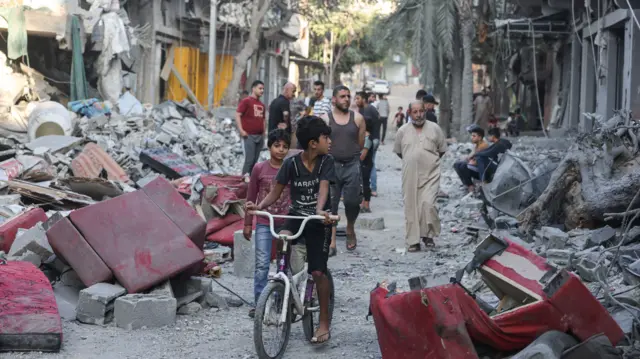 A Palestinian boy on his bicycle looks at destroyed buildings following Israeli bombardment of a refugee camp in the central Gaza strip