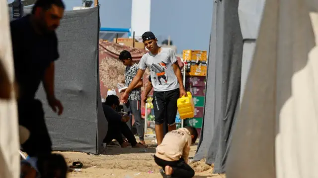 Palestinians, who fled their houses amid Israeli strikes, take shelter in a tent camp at a United Nations-run centre in Khan Younis, Gaza