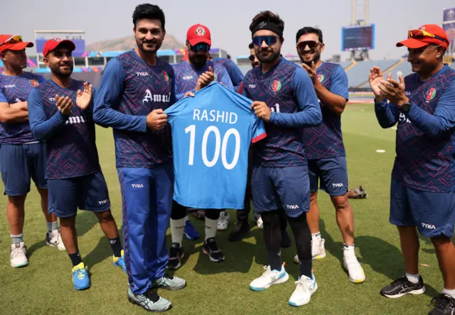 Rashid Khan being presented with a shirt with 'Rashid 100' on the back to mark his 100th ODI appearance