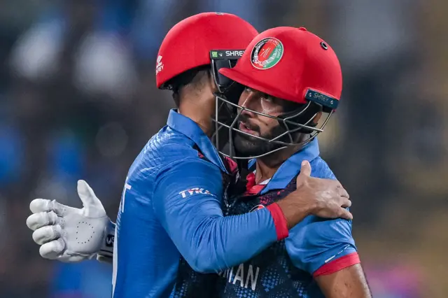 Afghanistan's captain Hashmatullah Shahidi celebrates with teammate Azmatullah Omarzai (L) after scoring a half-century (50 runs) during the 2023 ICC Men's Cricket World Cup one-day international (ODI) match between Afghanistan and Sri Lanka