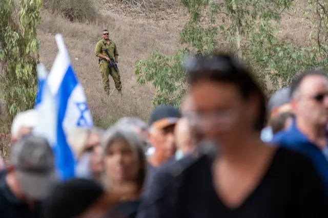 IDF Soldiers stand guard near the entrance to the funeral for Lili Itamari, 63, and Ram Itamari