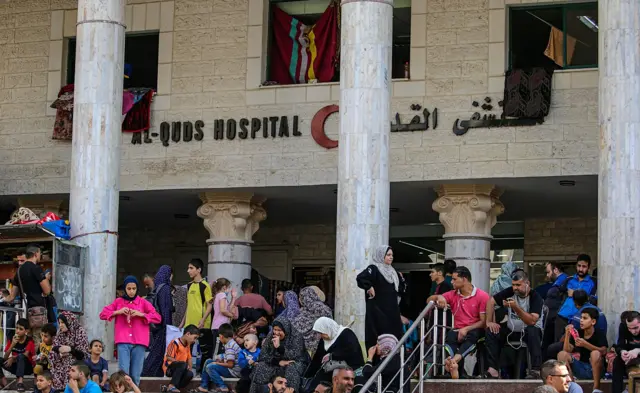 Lots of people sitting and standing outside Al Quds hospital