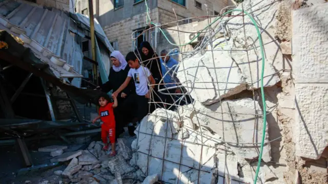 Palestinians seen going out from a damaged building following an Israeli military raid in a Jenin refugee camp in the occupied northern West Bank.