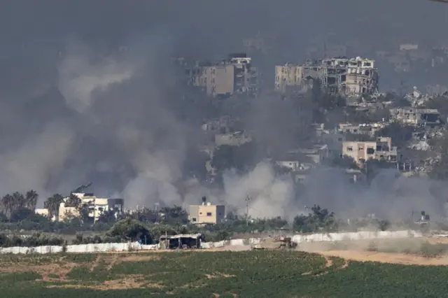 Israeli tanks manoeuvre inside the Gaza Strip, smoke is rising nearby from buildings that have been devastated by fighting