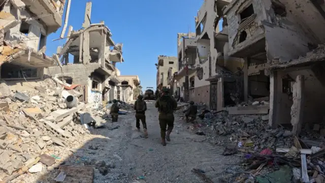 IDF troops walk among destroyed buildings in Gaza