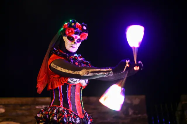 A Halloween performer spins beacons of light