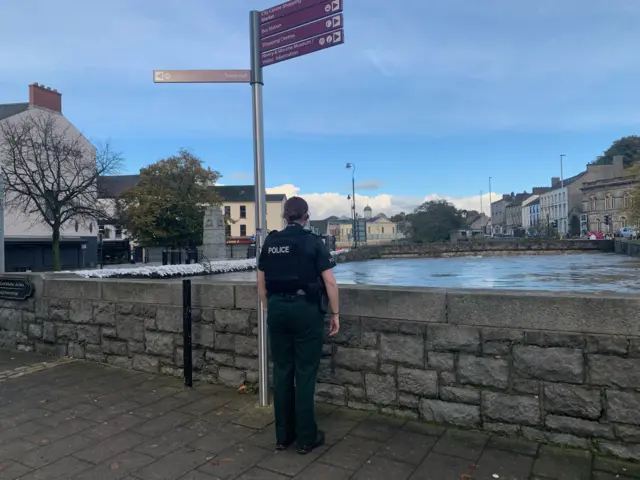 Police officer standing in front of river wall in Newry