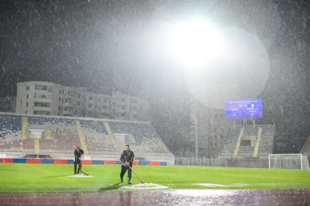 Ground staff clear the pitch of rain