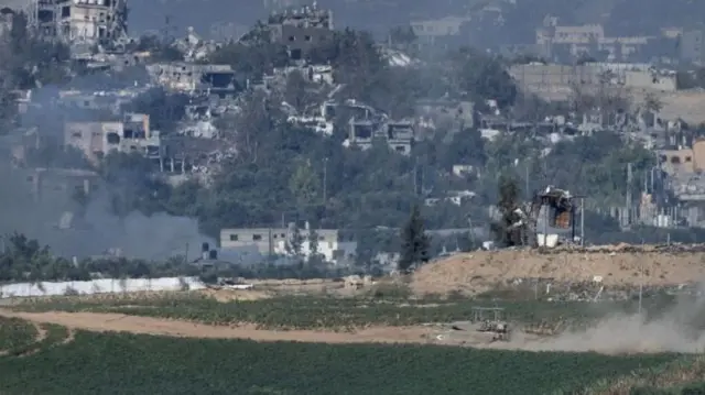 An Israeli tank (foreground) moves through the Gaza Strip