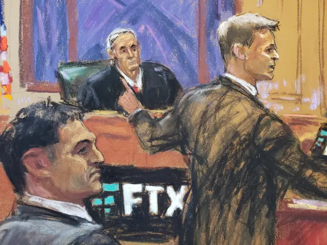 Drawing of Sam Bankman-Fried in grey suit seated, judge in background, lawyer in tan suit pointing finger on the side