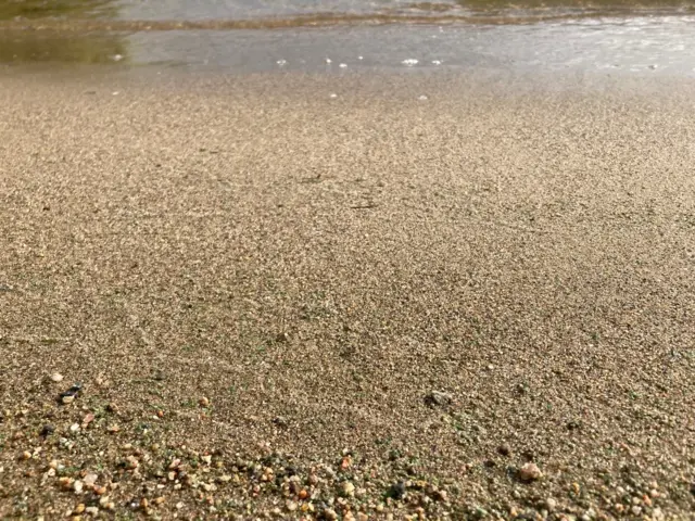 Sandy ground and clear water shows a little bit of foam