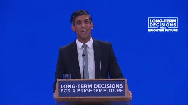 Rishi Sunak speaking in front of a blue background