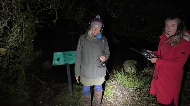 Radio presenter and production staff in warm coats in the dark