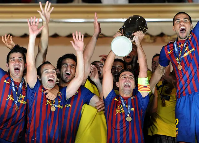 Xavi Hernandez of FC Barcelona holds the trophy aloft amid his teammates