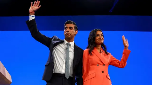 Sunak and his wife wave on stage at conference