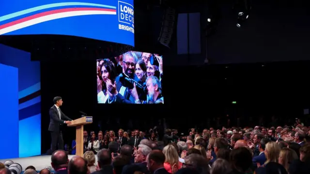 British Prime Minister Rishi Sunak speaks on stage at Britain's Conservative Party's annual conference