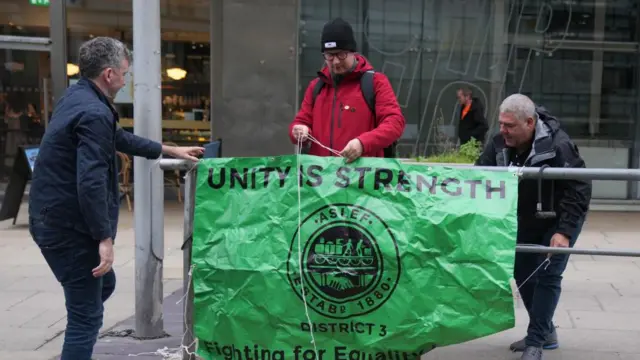 Striking workers hold up a sign reading "unity is strength"