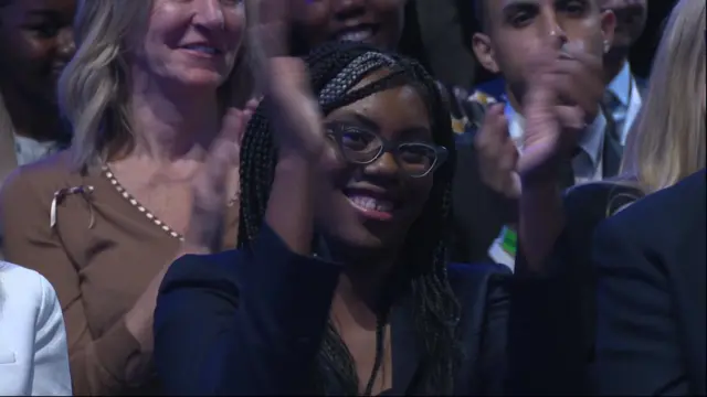 Kemi Badenoch applauds as she listens to Sunak's speech