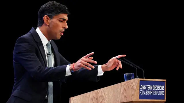 Rishi Sunak points as he speaks from the stage