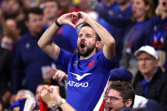 A fan of France makes a heart shape with their hands