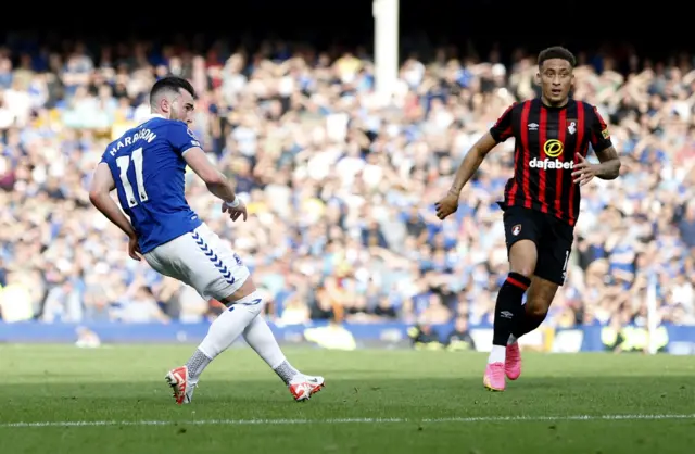 Harrison lobs the ball towards goal under pressure from a defender.