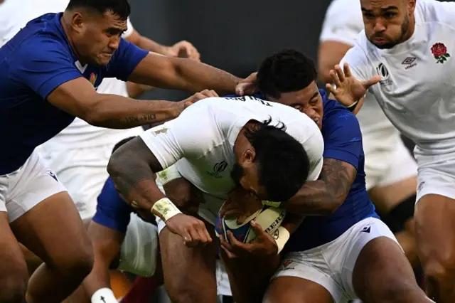 England's centre Manu Tuilagi is tackled by Samoan players