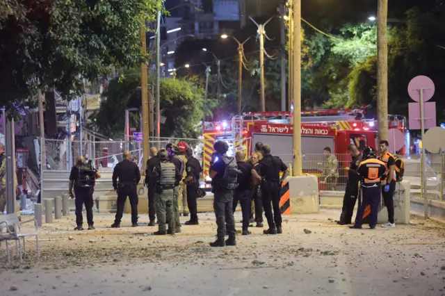 Firefighters and rescue workers stand outside a residential building hit by a rocket in Tel Aviv