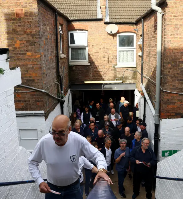 Tottenham fans make their way through the back entrance to the away end at Kenilworth Road.