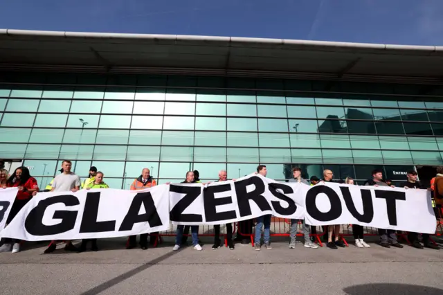 United fans gather behind a banner reading 'Glazers Out'